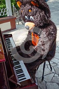 actor dressed as bear plays music on piano on the photo