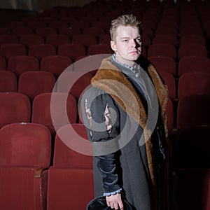 Actor dressed historical costume in interior of old theater.