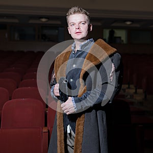 Actor dressed historical costume in interior of old theater.