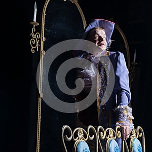 Actor dressed historical costume in interior of old theater.