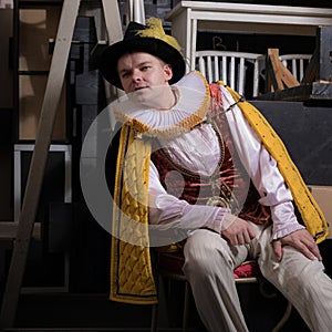 Actor dressed historical costume in interior of old theater.