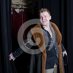 Actor dressed historical costume in interior of old theater.