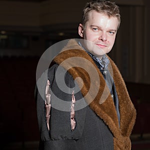 Actor dressed historical costume in interior of old theater.