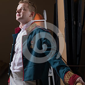 Actor dressed historical costume in interior of old theater.