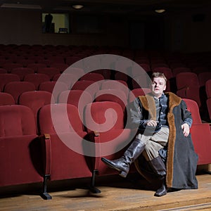 Actor dressed historical costume in interior of old theater.