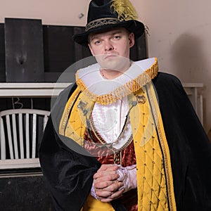 Actor dressed historical costume in interior of old theater.