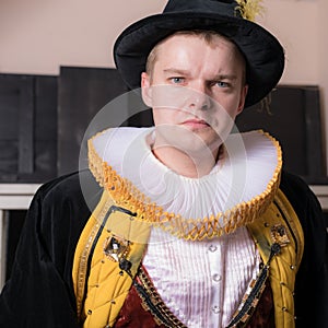 Actor dressed historical costume in interior of old theater.