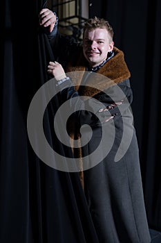 Actor dressed historical costume in interior of old theater.