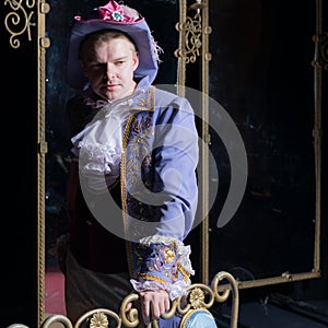 Actor dressed historical costume in interior of old theater.