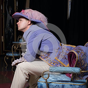 Actor dressed historical costume in interior of old theater.