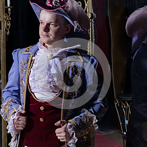 Actor dressed historical costume in interior of old theater.