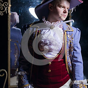 Actor dressed historical costume in interior of old theater.