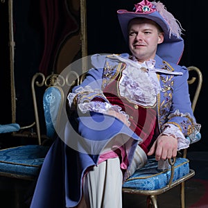 Actor dressed historical costume in interior of old theater.