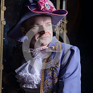 Actor dressed historical costume in interior of old theater.