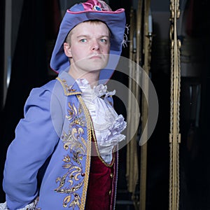 Actor dressed historical costume in interior of old theater.