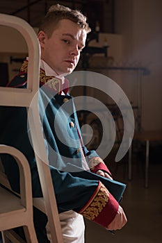 Actor dressed historical costume in interior of old theater.