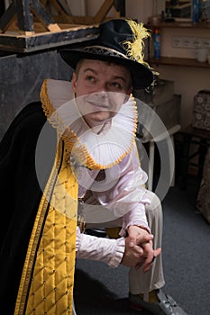 Actor dressed historical costume in interior of old theater.