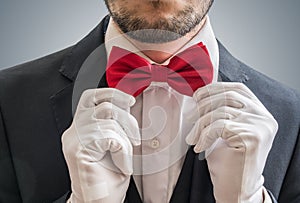 Actor or illusionist in white gloves is taking a red bowtie