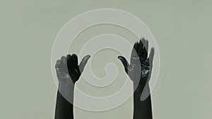 Actor mime with black hands shows gesture goodbye on a gray background