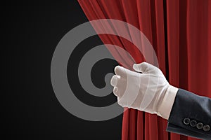 Actor is pulling red curtains in theatre with hand