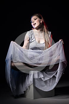 Actress in a grey dress on a dark stage