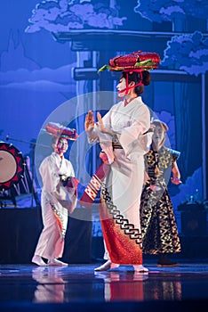 Actresses in traditional kimono and hats dancing with taiko drummer