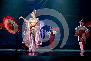 Actresses in traditional white and red kimono and fox masks dancing with umbrella and fans