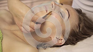 Acupressure on a female face. Chinese alternative massage with scraper gouache