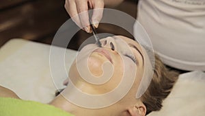 Acupressure on a female face. Chinese alternative massage with scraper gouache