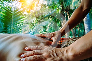 Acupressure massage in spa centre outdoor. Woman at acupressure back massage, masseur`s hands close up. Body therapy for healthy