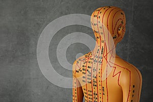 Acupuncture model. Mannequin with dots and lines on dark grey background, space for text