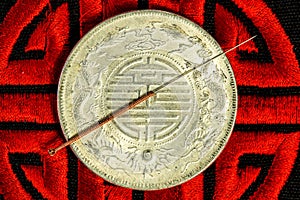 Acupuncture needle on Chinese coin and symbol for immortality