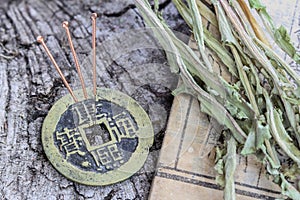 Acupuncture needles on an ancient Chinese bronze coin and an old medical book