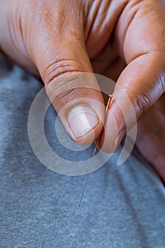 Acupuncturist doctor holding between his fingers a steel needle