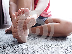 Acute foot pain of thai Asian women, Using hand massage on feet to relieve severe sore feet. photo