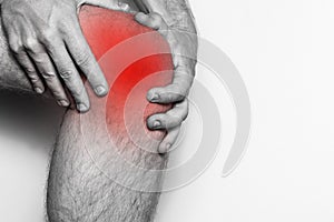 Acute pain in a knee joint, close-up. Monochrome image, on a white background. Pain area of red color