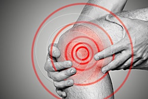 Acute pain in a knee joint, close-up. Monochrome image, on a white background. Pain area of red color photo