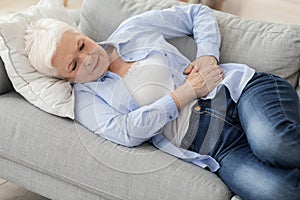 Acute Pancreatitis. Sad elderly woman holding her abdomen, suffering from stomach ache