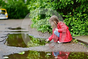 Ad girl playing in a puddle on rainy summer day