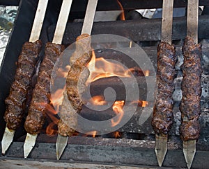 Adana kebab ground lamb minced meat on skewer on grill over charcoal