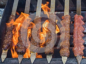 Adana kebab ground lamb minced meat on skewer on grill over charcoal