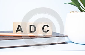 ADC acronym on building blocks supported by two different size pencils. Copy space photo