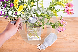 Add grounded acetylsalicylic acid tablet into vase keep flowers photo