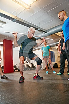 Add this pvc workout into your training. a senior man doing pvc exercises while a group of people watch on.