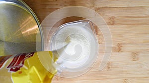 Add semolina in a measuring plastic Cup on the background of a wooden table