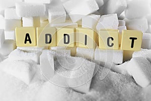 Addict block letters word on pile of sugar cubes close up in sugar addiction concept