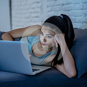 Addicted beautiful woman working and chatting on her laptop late at night looking exhausted