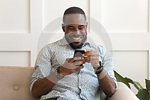 Addicted happy smiling african american guy using mobile phone.