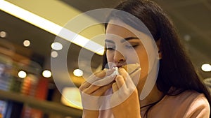 Addicted to fast food lady eating hamburger in restaurant, hungry student snack