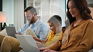 Addicted to modern technology dad mom son using different gadgets happy Caucasian family spend time together parents